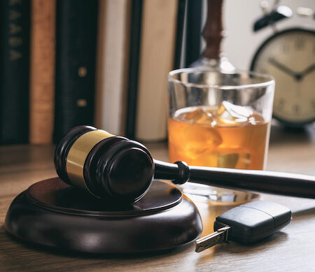 DUI concept. Law gavel, alcohol and car keys on a wooden desk, dark background